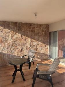 two chairs and a table in a room with a stone wall at Casa Cedro Y Olivo in Gutiérrez Zamora