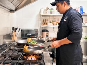 a man cooking food in a pan on a stove at BougainVilla - Oceanfront villa with Cook, ideal for Weddings and Events in Keramas