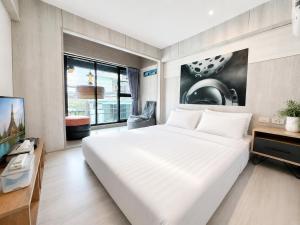 a bedroom with a large white bed and a tv at Sleep Walker Poshtel in Chiang Mai