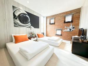 a bedroom with two beds and a brick wall at Sleep Walker Poshtel in Chiang Mai