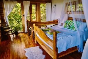 a bedroom with a wooden bed with blue sheets and windows at Jungle Spirit Treehouse in Cahuita
