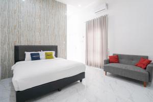 a bedroom with a bed and a chair in it at Urbanview Hotel Nimara Ngawi by RedDoorz in Ngawi