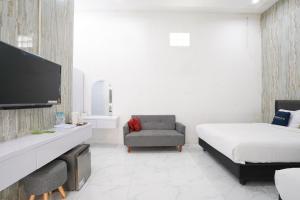 a bedroom with a bed and a tv and a chair at Urbanview Hotel Nimara Ngawi by RedDoorz in Ngawi