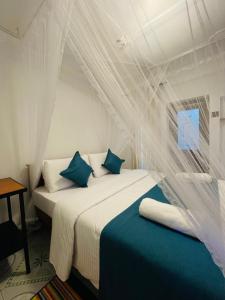 a bedroom with a bed with white sheets and blue pillows at Ella Solara Heaven in Ella