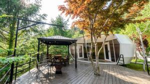 a house on a deck with a tree at Gapyeong Pine4rest Glamping in Gapyeong
