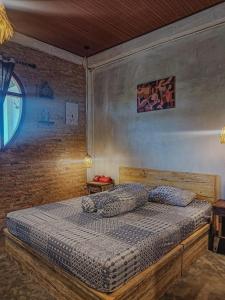 a bed in a bedroom with a brick wall at Loti Guest House in Kupang