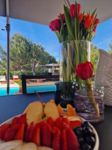 a plate of fruit with flowers and a vase of tulips at La Villa Monarque in Cap d'Agde
