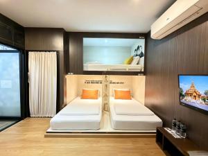 two beds in a room with a tv at Sleep Walker Poshtel in Chiang Mai
