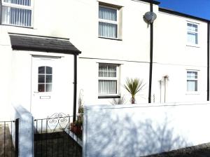 a white house with a fence in front of it at Carland Cross in Newquay