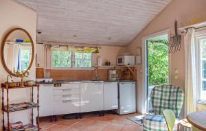 a kitchen with white cabinets and a sink and a mirror at Stunning Home In Borrby in Borrby