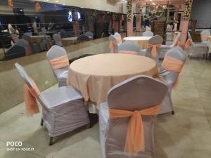 a table with chairs and a table with an orange ribbon at Hotel Welcome Palace in Surat