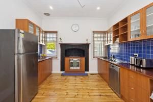 a kitchen with wooden cabinets and a fireplace at Barnard Bungalow in Bendigo