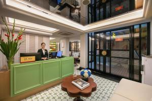 a woman standing at a counter in a lobby at Hoan Kiem Legend Ha Noi Hotel in Hanoi