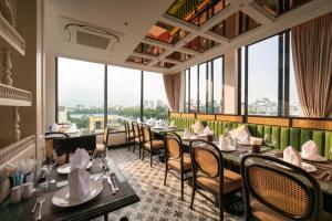 a restaurant with tables and chairs and large windows at Hoan Kiem Legend Ha Noi Hotel in Hanoi