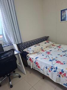 a bedroom with a bed and a chair and a window at Lar doce lar da Lu in Curitiba