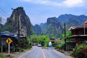 a street in a village with mountains in the background at ภูผา เฮ้าส์ รีสอร์ท in Ban Mung