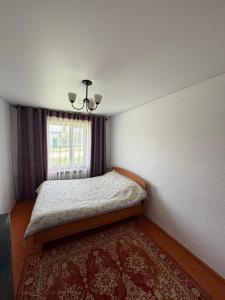 a small bedroom with a bed and a window at M-otel in Karakol