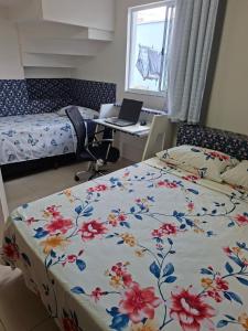 a bedroom with two beds and a desk with a laptop at Lar doce lar da Lu in Curitiba