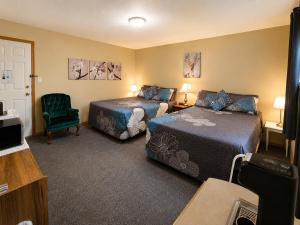 a hotel room with two beds and a chair at NEWCASTLE COUNTRY INN in Drumheller