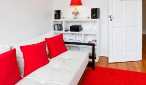 vitoria flat في بورتو: أريكة بيضاء مع وسائد حمراء في غرفة المعيشة