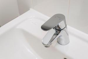 a silver sink faucet in a white bathroom at Point A Hotel London Shoreditch in London