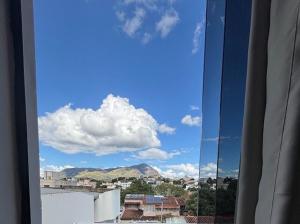 a window with a view of a city and clouds at Super Apt morada do Vale in Governador Valadares