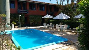 Una piscina con sillas y sombrillas al lado de una casa. en Hotel Trevo do Porto, en Porto Seguro