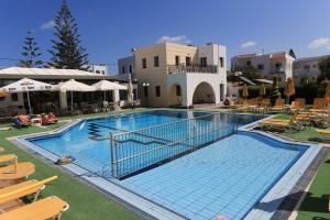 a large swimming pool with chairs and a building at Artemis Apartments in Gouves