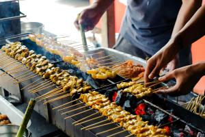 a group of people cooking food on a grill at Snap Sukhumvit 1 - BTS Nana in Makkasan