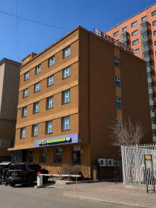 a large brown building with cars parked in front of it at Sats hotel in Ulaanbaatar