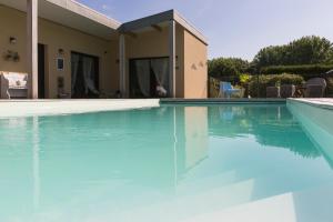 a swimming pool with blue water in front of a house at Les Keriaden's in Pleudihen