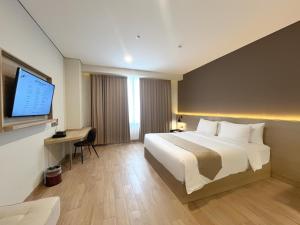 a hotel room with a bed and a flat screen tv at Prime UMY Hotel Convention & Dormitory in Yogyakarta