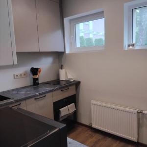 a kitchen with white cabinets and a window at The Dacha apartment in Jūrmala