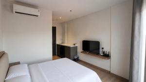 a bedroom with a white bed and a flat screen tv at SleepRest Azure Suites in Bagam