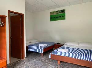 a room with two beds and a door to a bedroom at Finca Hotel La Potranca in Acacías