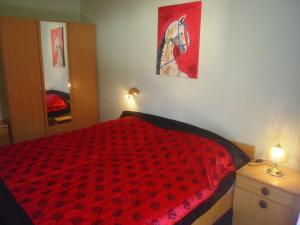 a bedroom with a red bed with a horse painting on the wall at Ferienwohnungen Strasser in Stockenboi