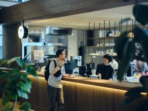 Ein Mann, der am Tresen eines Restaurants steht in der Unterkunft Arbor Onomichi in Onomichi