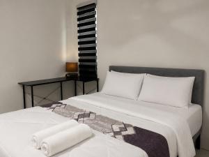 a bedroom with two beds with white sheets and a table at The Bunker StudioStay in Arau