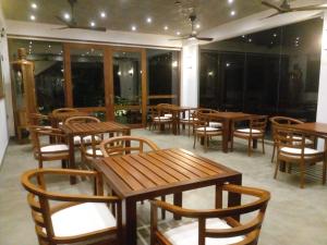 a restaurant with wooden tables and chairs and windows at Moonstone herbal villa in Balapitiya