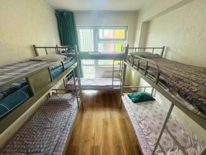 a room with three bunk beds and a window at Sunrise Guesthouse UB in Ulaanbaatar