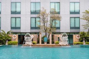 a swimming pool with two statues in front of a building at Hyatt Regency Bangkok Suvarnabhumi Airport in Lat Krabang