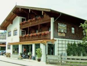 un edificio con un balcón con flores. en Metzgerei und Gästehaus Grandauer, en Nussdorf am Inn