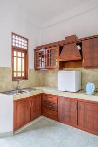 a kitchen with wooden cabinets and a white refrigerator at Airport Green View Hotel Katunayake in Andiambalama