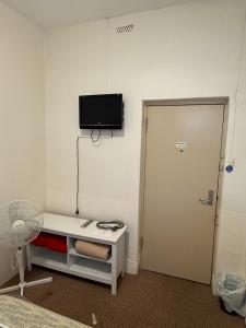 Ein Zimmer mit einem Fernseher an der Wand neben einer Tür in der Unterkunft Riverton Hotel in Riverton