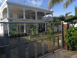 a white house with a balcony and a fence at Beejan Mansions in Roches Noires