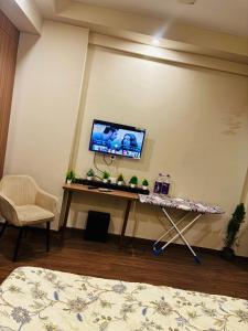 a room with a table and a tv on a wall at Apex Hub in Greater Noida