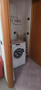 a washing machine in a room with a sign on the wall at Residenza dei pini lacchiarella in Lacchiarella +8 photos