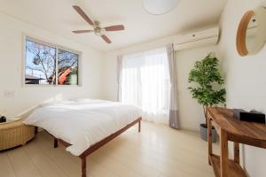 a bedroom with a bed and a ceiling fan at Halema in Ichinomiya
