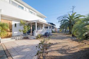 a white house with palm trees in front of it at Halema in Ichinomiya