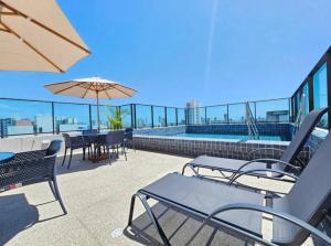 a patio with a table and chairs and an umbrella at FLAT LUXO em BOA VIAGEM Prox PRAIA, SHOPPING e AEROPORTO in Recife